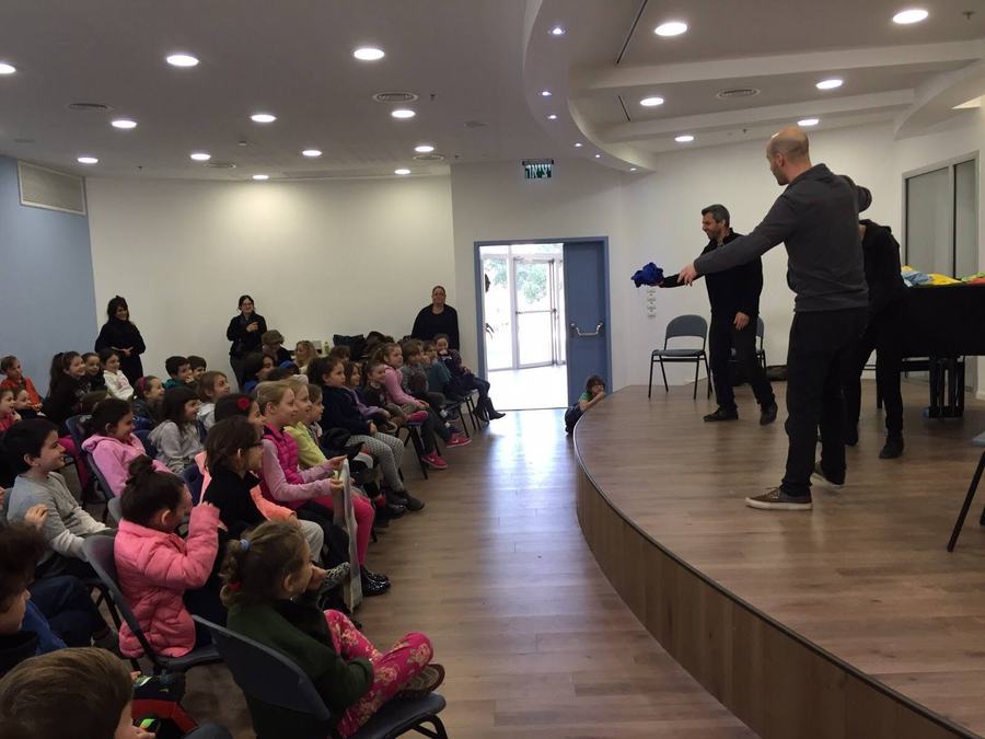 שחקן על הבמה מול קהל תלמידים צעירים
